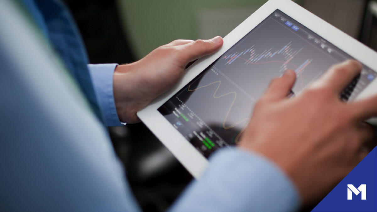 Close-up of person holding tablet with market data on screen