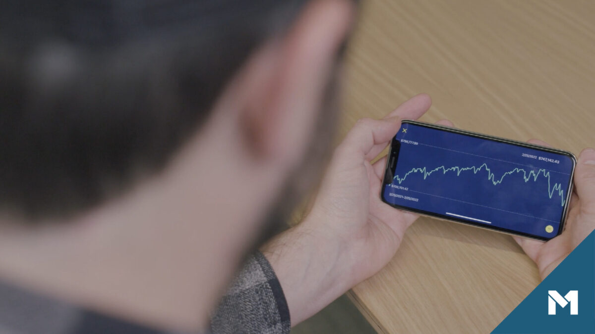 Person looking at smartphone displaying stock market data in a line graph