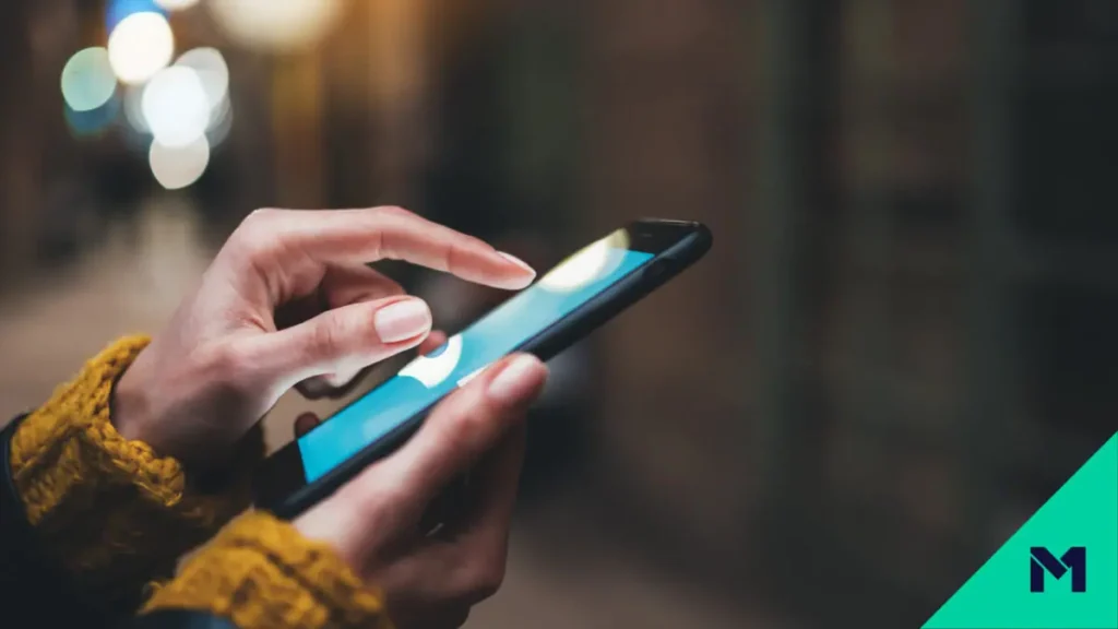 Persons hands using phone on sidewalk