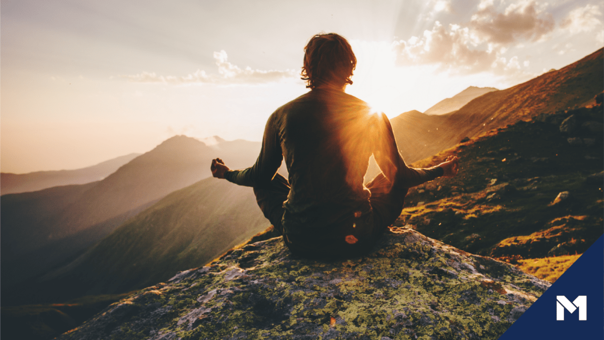 Person meditating outside during sunset