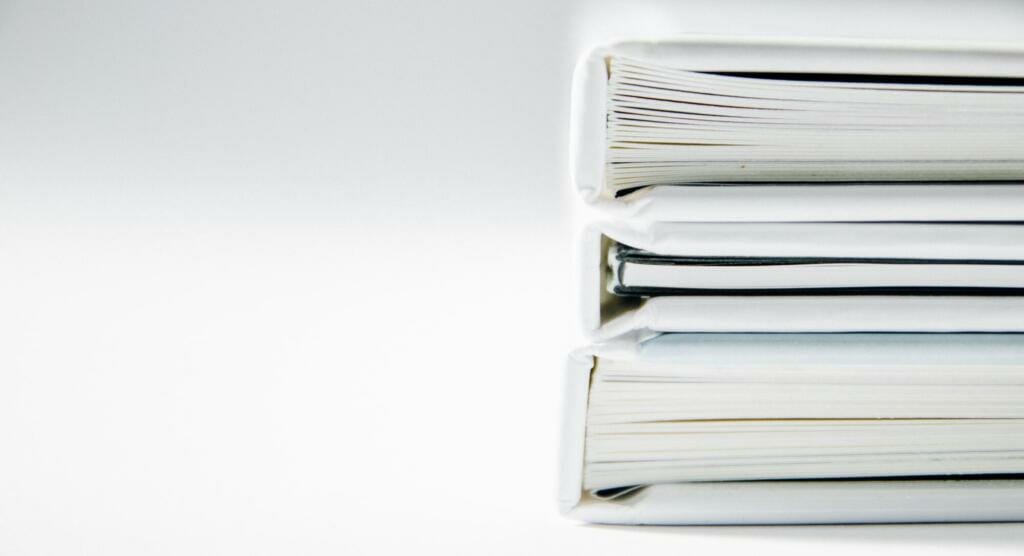 Stack of white binders full of financial documents