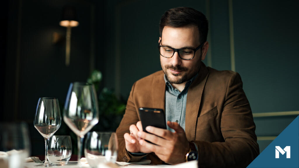 Wealthy man at a restaurant using digital bank on smartphone