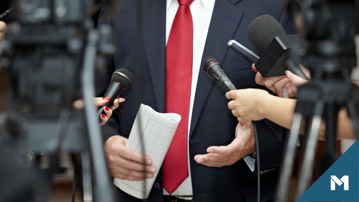 Politican holding a press conference with reporters holding microphones