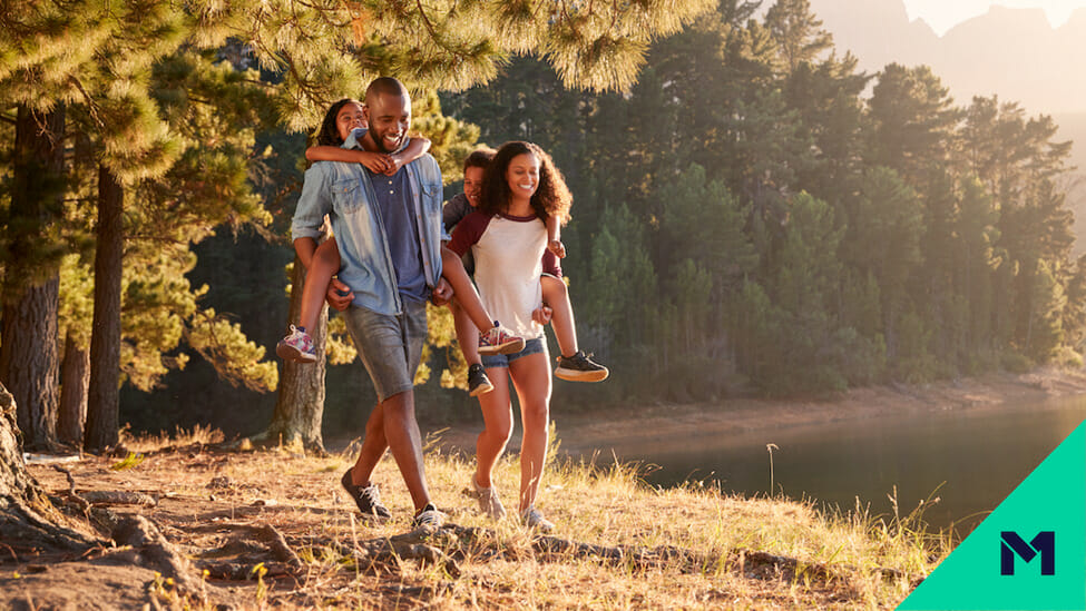 Parents giving kids piggyback ride in the woods