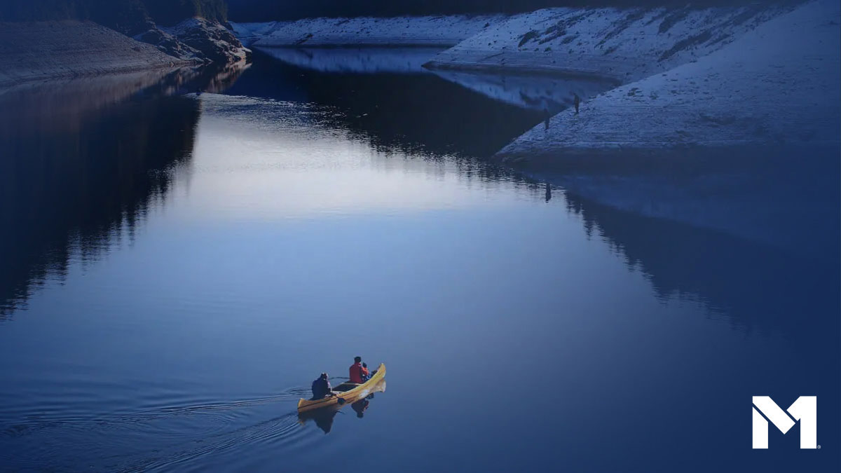 Two people paddling on a canoe down a wide lake.